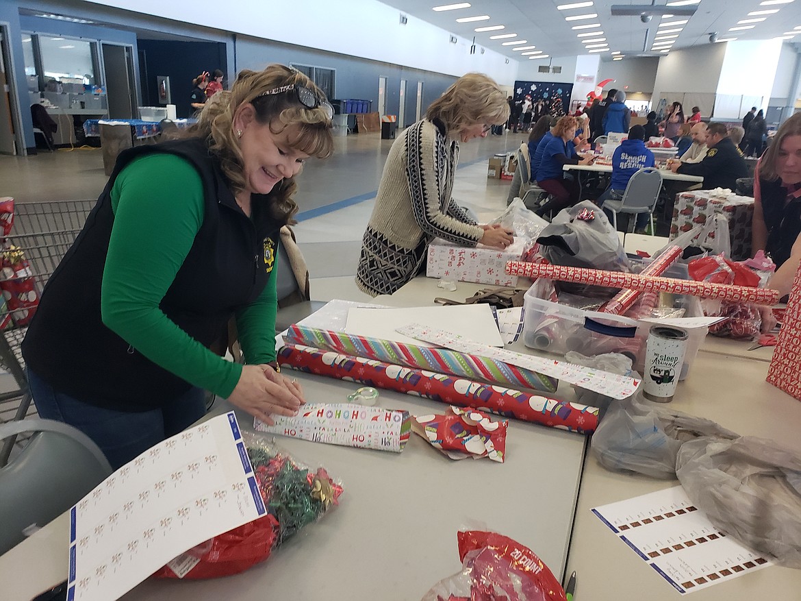 Volunteers (from left) Marcie Galloway and Rochelle Nilles wrap gifts children bought for their families during the Holidays and Heroes event on Dec. 4 in the Greyhound Park and Event Center. While they wrap, children can pull candy canes from Christmas trees and enjoy cookies and hot chocolate wrapped in new blankets and toys before they deliver their presents to their families.