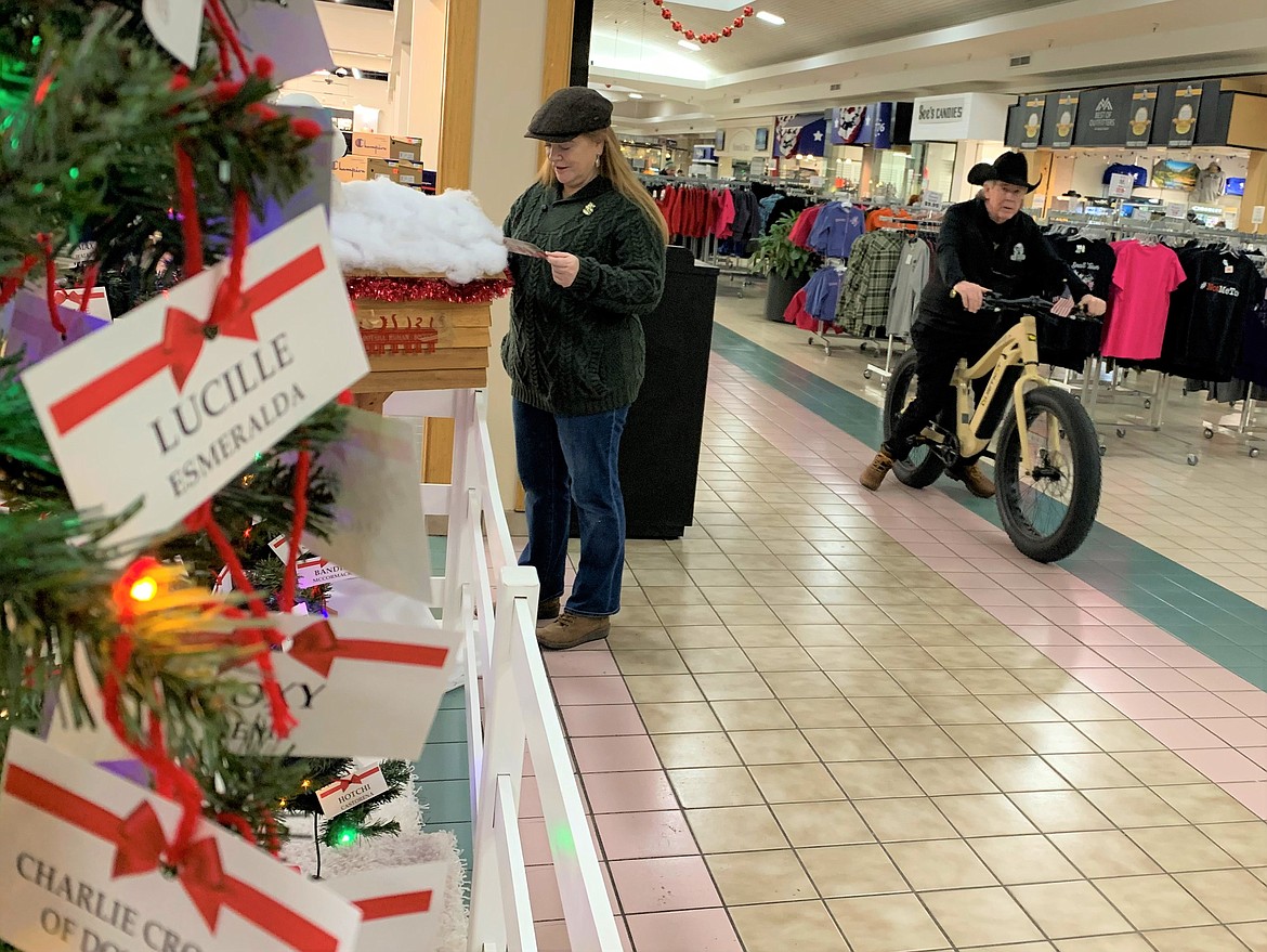 Silver Lake Mall owner Dave Knoll rides an electric bike pass the "Lights of Love" display to benefit the Kootenai Humane Society on Sunday evening.