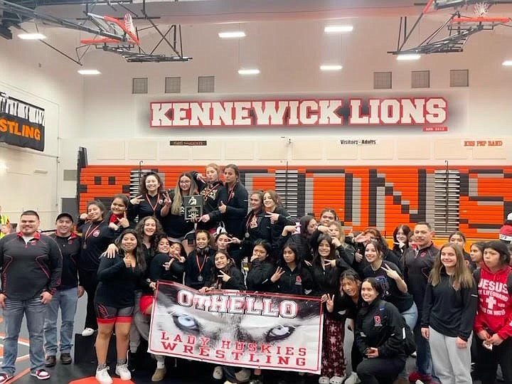 Othello wrestlers pose with a team banner at the Kennewick Lioness Invite on Saturday.