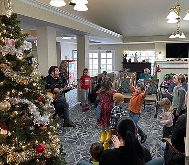 Scott Dodson strums the guitar Monday as kids dance and sing along during an intergenerational Christmas storytime at Honeysuckle Senior Living in Hayden. Honeysuckle partnered with Auburn Crest Hospice to bring generations together for the magic of the season. Usborne Books representative Sharon Gross Funkhouser, not pictured, read holiday tales as Dodson provided the music.