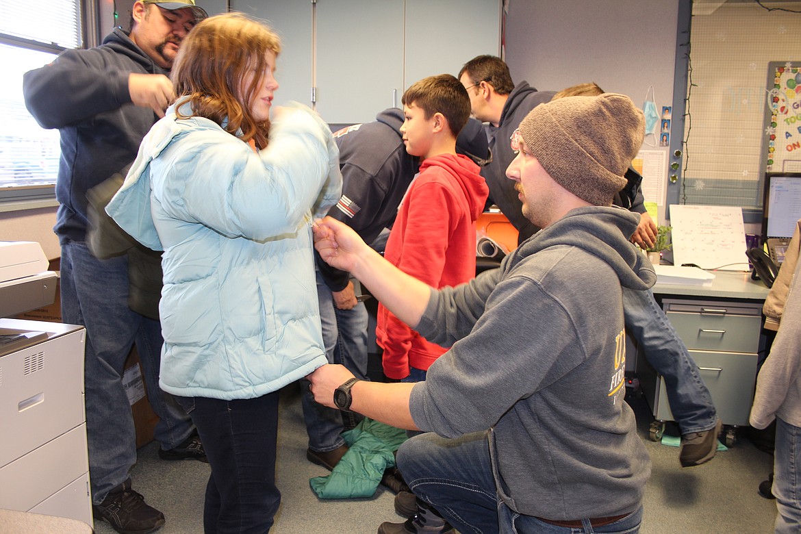 Garrett Fletcher of the Moses Lake Fire Department zips up a brand-new coat for Abigail Lynch.