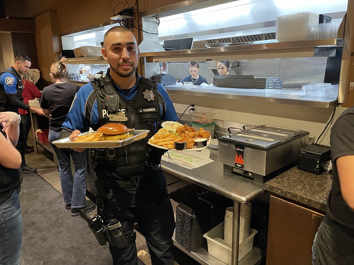 Warden Police Department Officer Joel Torres carries out an order from the kitchen at Rock Top Burgers and Brew on Wednesday.
