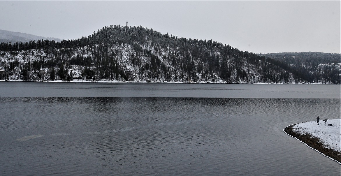 An oil sheen floats on the surface of Lake Coeur d'Alene on Thursday while Bozeman, Mont., photographer Jeff Brenner watches for bald eagles from the shoreline.