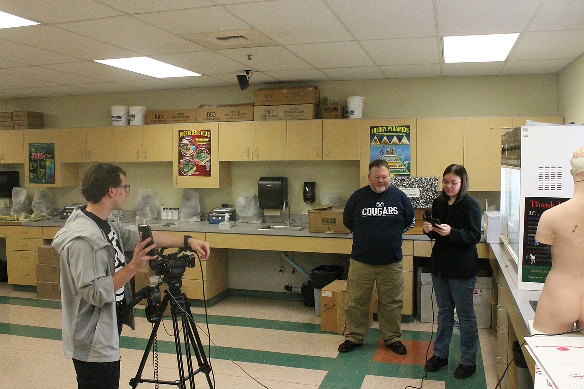 Katie Carlson, right, quizzes Royal High School teacher Jeremy Elliott on his Christmas favorites while Paden Livingston records the segment.