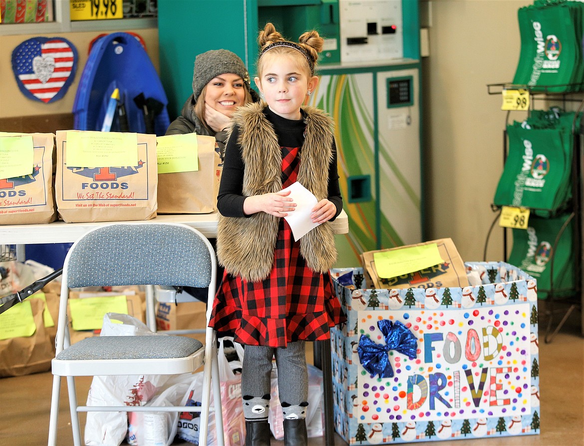 Lola Haycraft, joined by mom Kaela Haycraft, waits at Super 1 Foods in Hayden as she collects donations for food drive on Saturday.