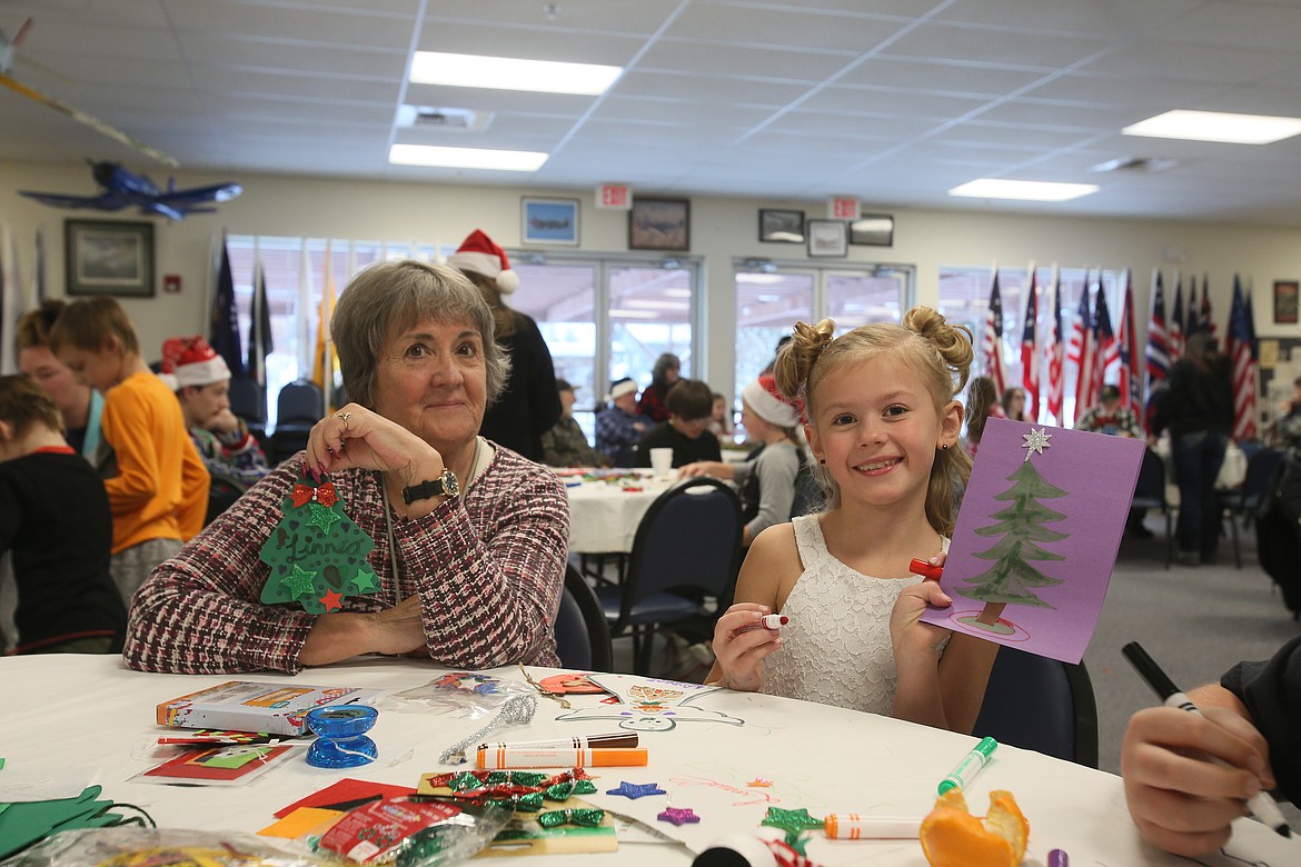 Grandma Beth Dagastine and granddaughter Linnea Leine, 7, show off cards and ornaments they made Saturday at the Post Falls American Legion's Christmas party.