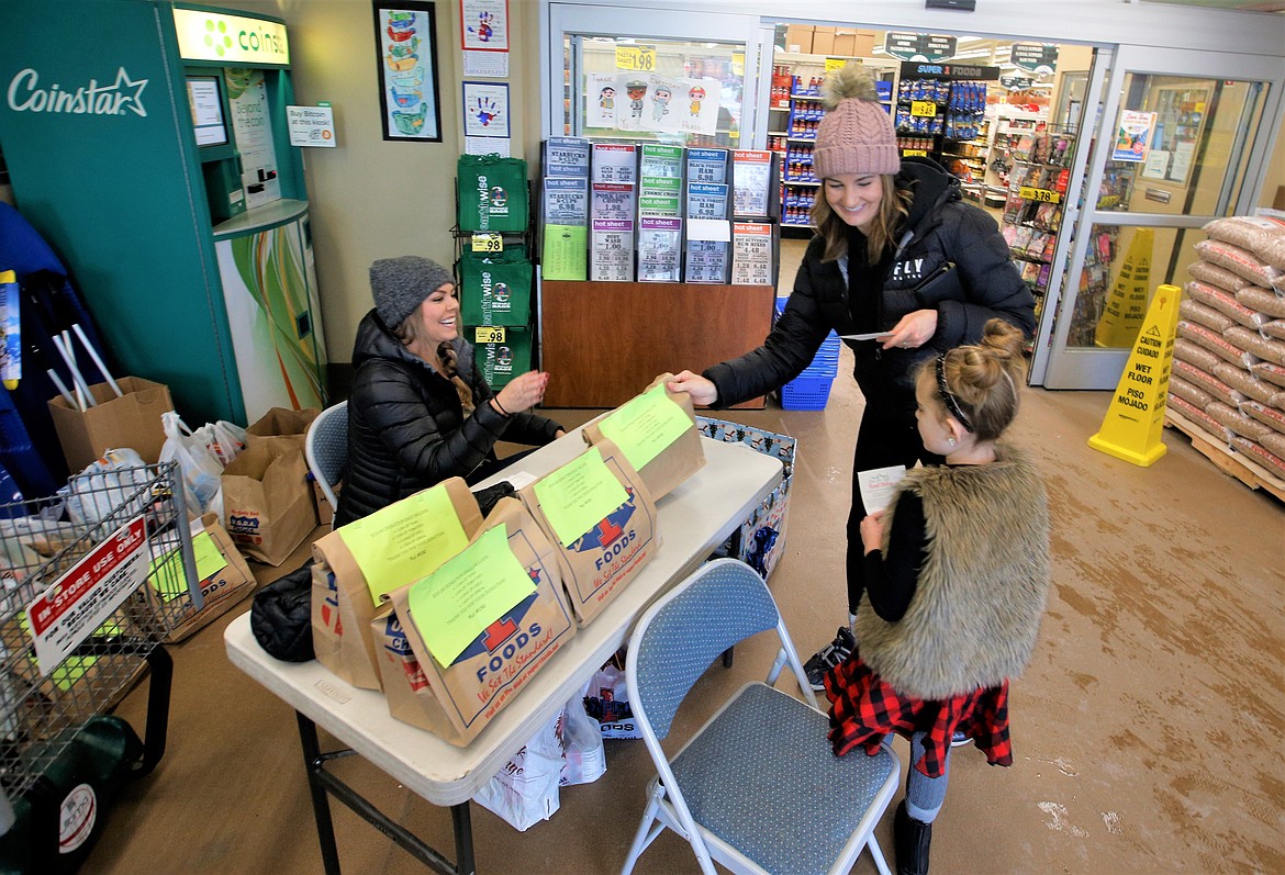 A customer of Super 1 Foods picks up a bag to make a donation to Lola Haycraft and her mother Kaela Haycraft for Lola's food drive on Saturday.