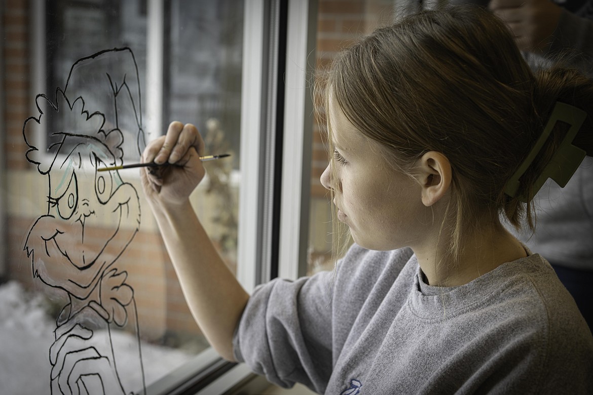 Freshman Madi Peele paints the Grinch on the Post Office window. (Tracy Scott/Valley Press)