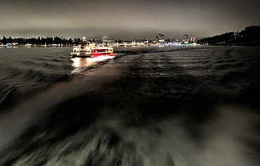 The lights of The Coeur d'Alene Resort and downtown Coeur d'Alene shine in the distance as a boat with Lake Coeur d'Alene Cruises heads across Lake Coeur d'Alene on a Journey to the North Pole on Sunday night.