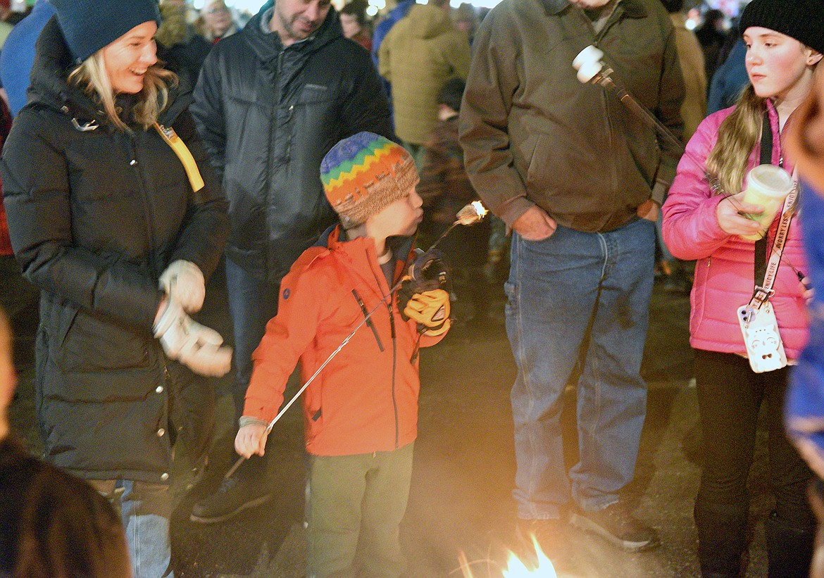Kids roast marshmallows over a fire pit at the Whitefish Christmas Stroll on Friday. (Whitney England/Whitefish Pilot)