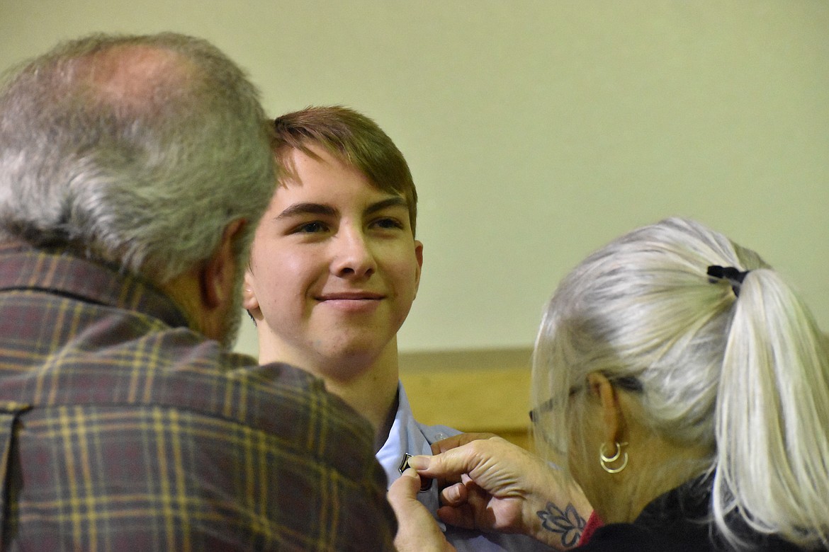 Cadet Master Sgt. Dylan Cruz smiles as his grandparents pin his new rank on his collar.