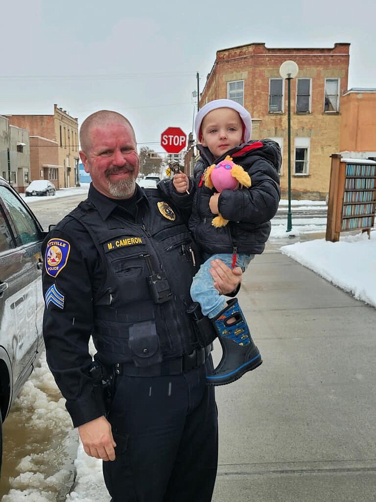 Ritzville Police Officer Mark Cameron poses with a child at the 2022 Ritzville Shop with a Cop event.