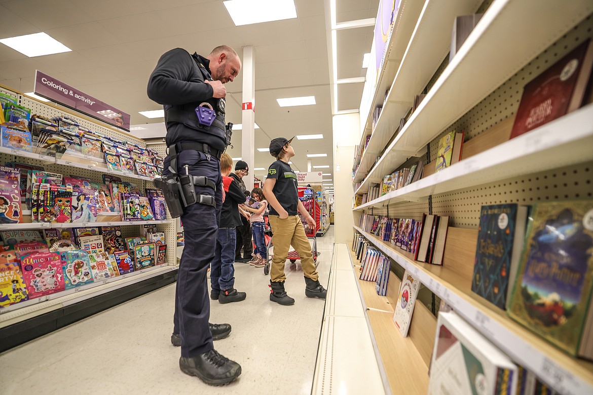 Chief Peters towers over the bookshelf with kids trying to find the right book for Christmas at Target for Shop with a Cop last week. (JP Edge photo)