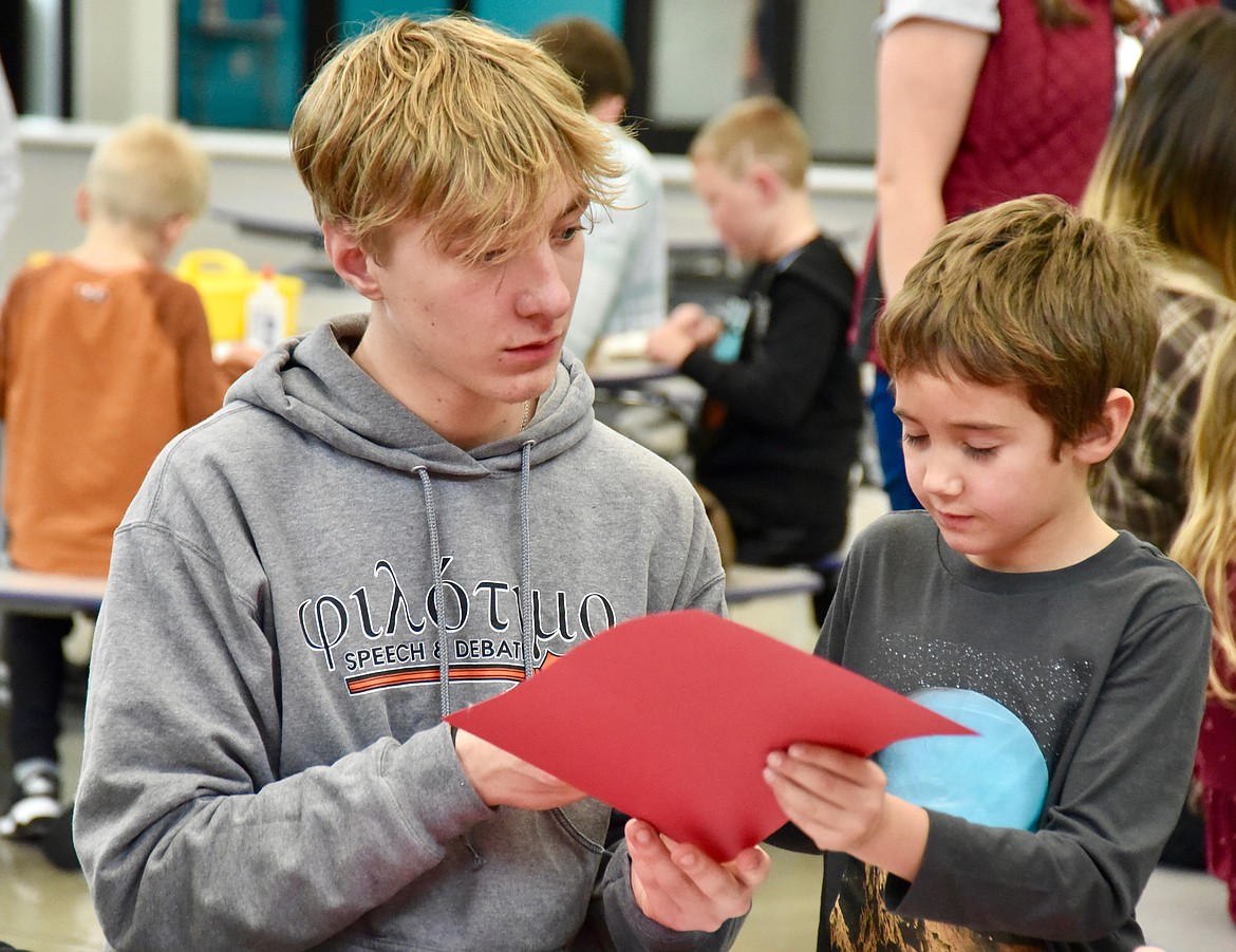 Flathead High School student Jack Blodgett works with first-grader Cooper Tanner at Rankin Elementary School Friday afternoon. FHS Speech and Debate team members spent time helping the younger students with making a paper Santa. (Heidi Desch/Daily Inter Lake)