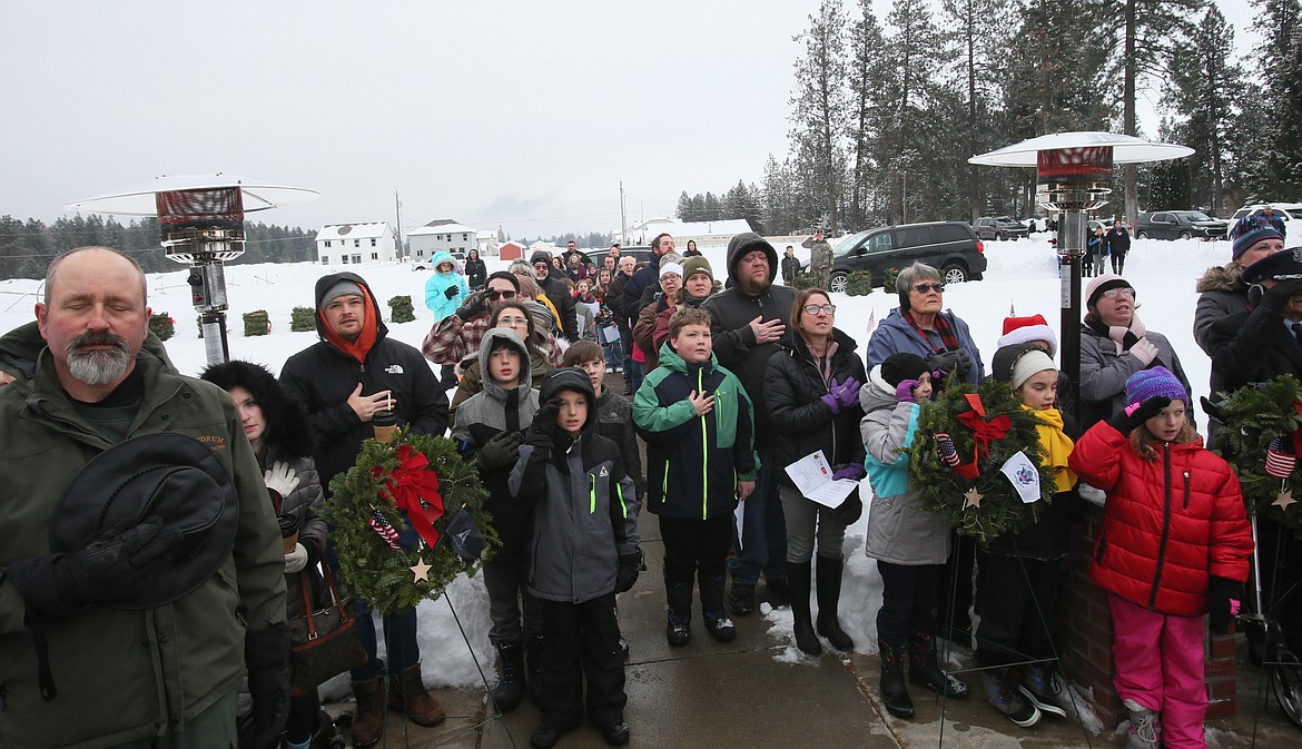 Attendees place their hands over their hearts Saturday morning as they recite the Pledge of Allegiance at the start of the Wreaths Across America event at Pinegrove Cemetery in Rathdrum. Nearly 270 wreaths were laid on veterans' gravesites in honor of their service as part of the annual wreath-laying event.