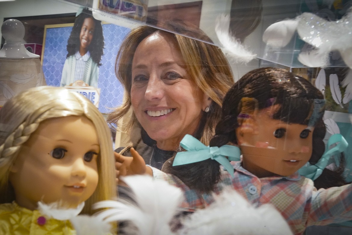 Jamie Cygielman, general manager and president at American Girl, poses behind a showcase of dolls during a press tour, Friday, Dec. 2, 2022, in New York. Cygielman said she first discovered interest from adults for toys of their own after the launch of the 17th historical doll Courtney Moore in late 2020. (AP Photo/Bebeto Matthews)