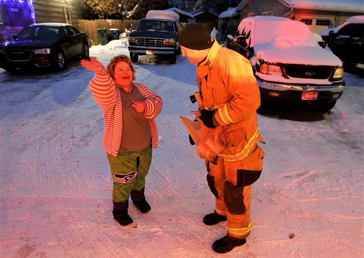 Crystal Teeters waves as firefighter Tom Hiltenbrand looks on Monday during the Mobile Santa Food Drive.