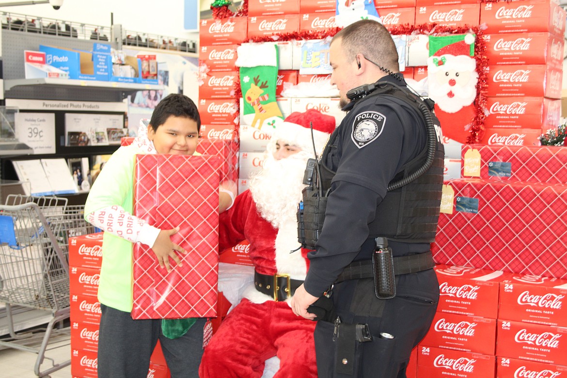 Jesus Camarillo (left) and his shopping buddy, Othello Police Department Officer Martin Garza, get their picture taken with Santa.