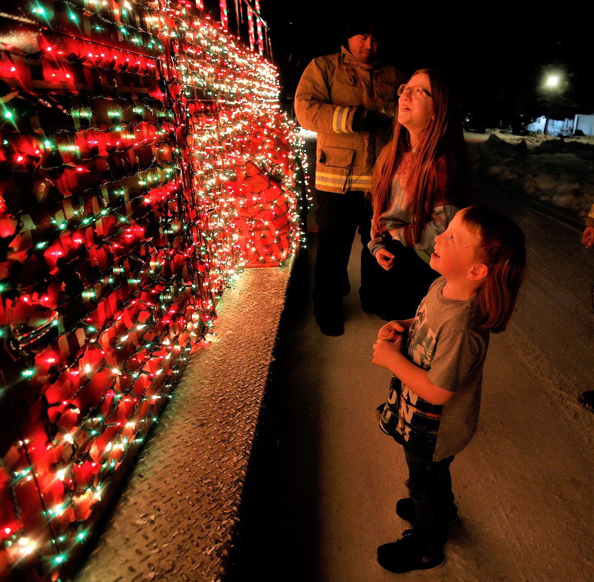 Taylor Gustin and brother Bradley greet Santa on Monday night joined by firefighter Travis Georgius.