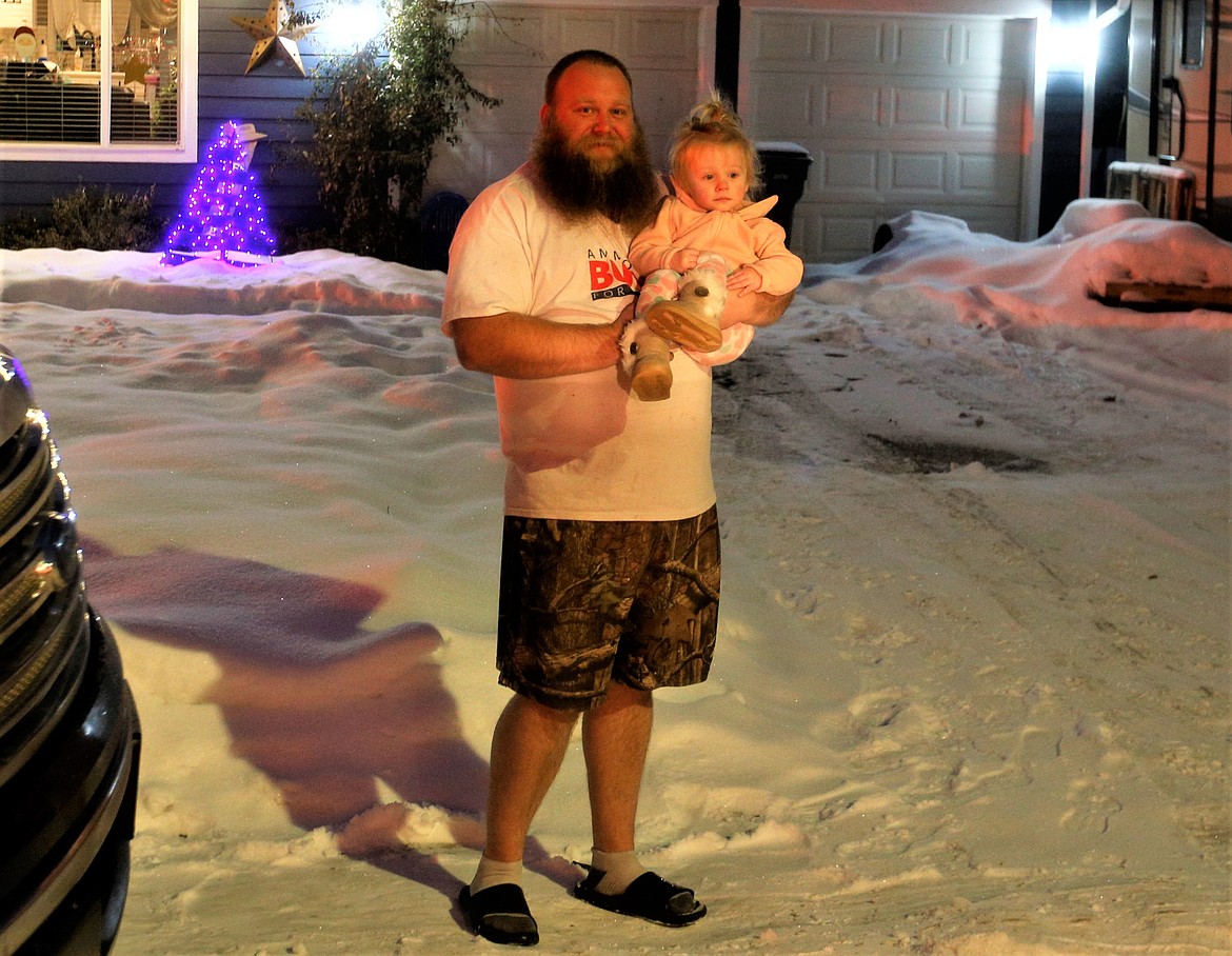 Brett Parsons holds daughter Millie as they wait to see Santa and make a donation Monday night.