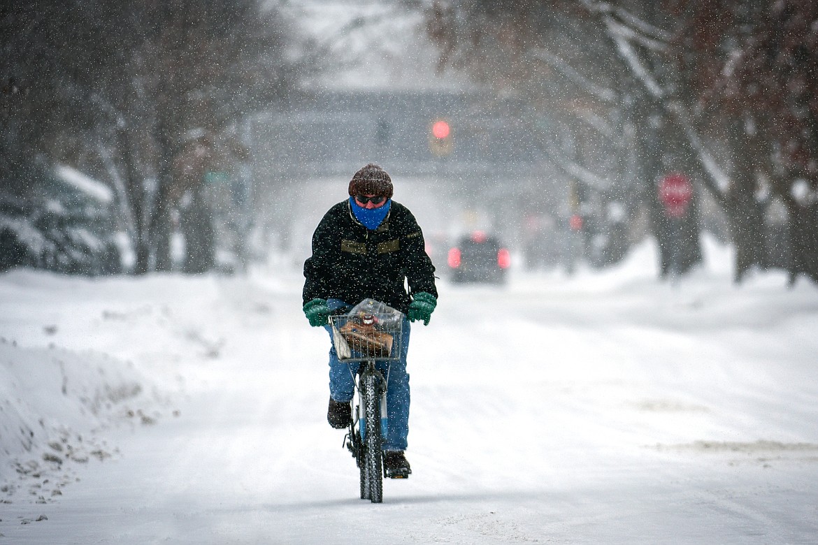 Kevin Kasperson rides his bicycle along Eleventh Street East as snow falls in Kalispell on Tuesday, Dec. 20. Kasperson was riding over to a friend's residence to help them with shoveling. (Casey Kreider/Daily Inter Lake)