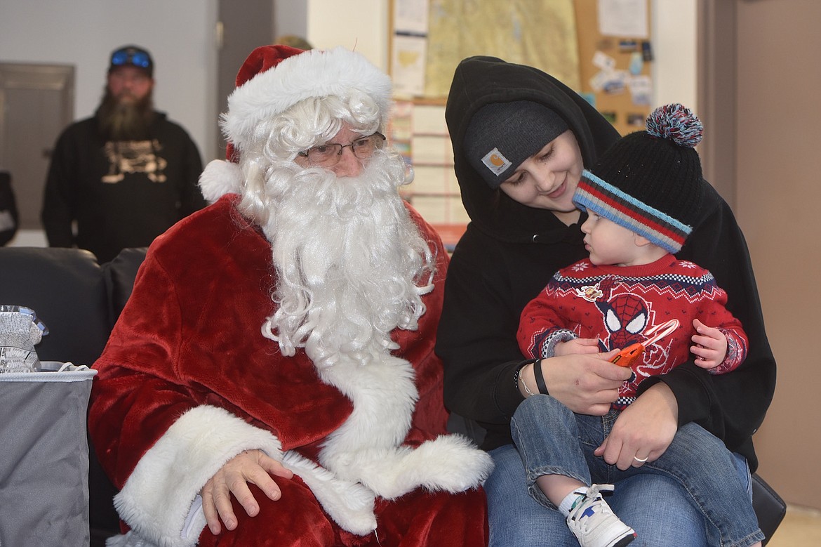 Troy youngster Tucker Raska and mom Sara Sawyer visit with Santa Claus Monday afternoon at the Libby Airport. (Scott Shindledecker/The Western News)