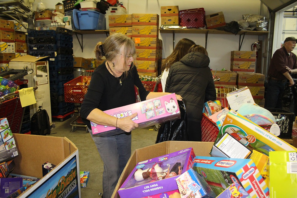 It’s a big box, but Sandi Casebolt maneuvers it into a bag for distribution at Operation Friendship toy pickup day.