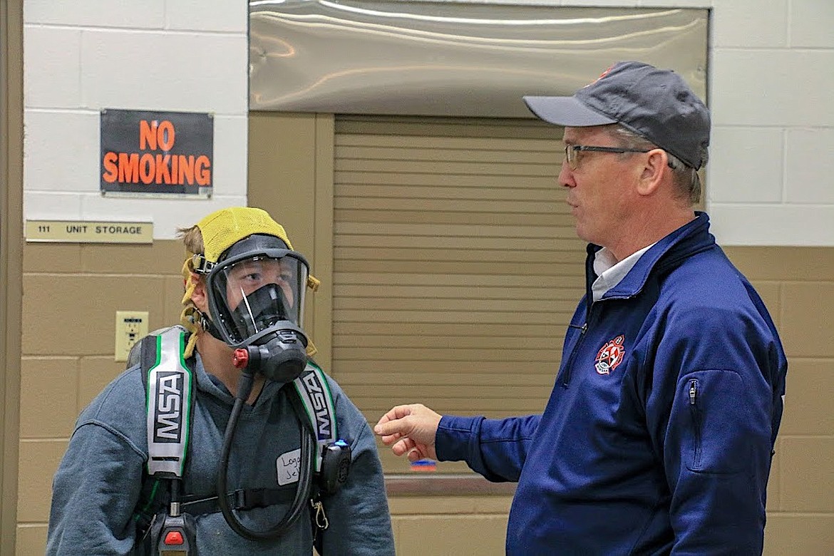 Libby Volunteer Fire Department Chief Steve Lauer illustrates the importance of a breathing apparatus to an area teen on Dec. 15. (Photo courtesy Jerica O'Neil)