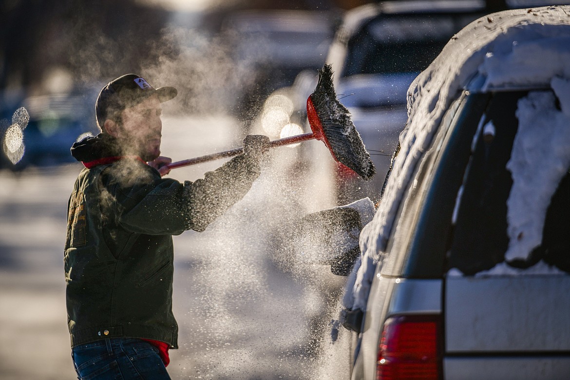 Jake Kinkel clears snow off his vehicle along Fourth Avenue East on Thursday, Dec. 22. (Casey Kreider/Daily Inter Lake)