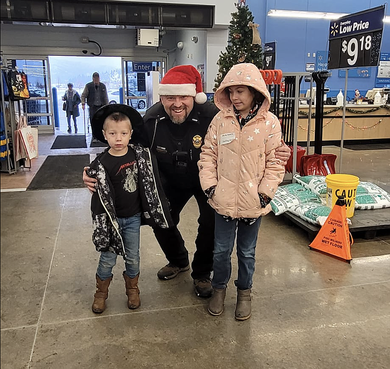 Osburn Police Department Lt. Jason Woody smiles for the camera with his assigned little shoppers last weekend.