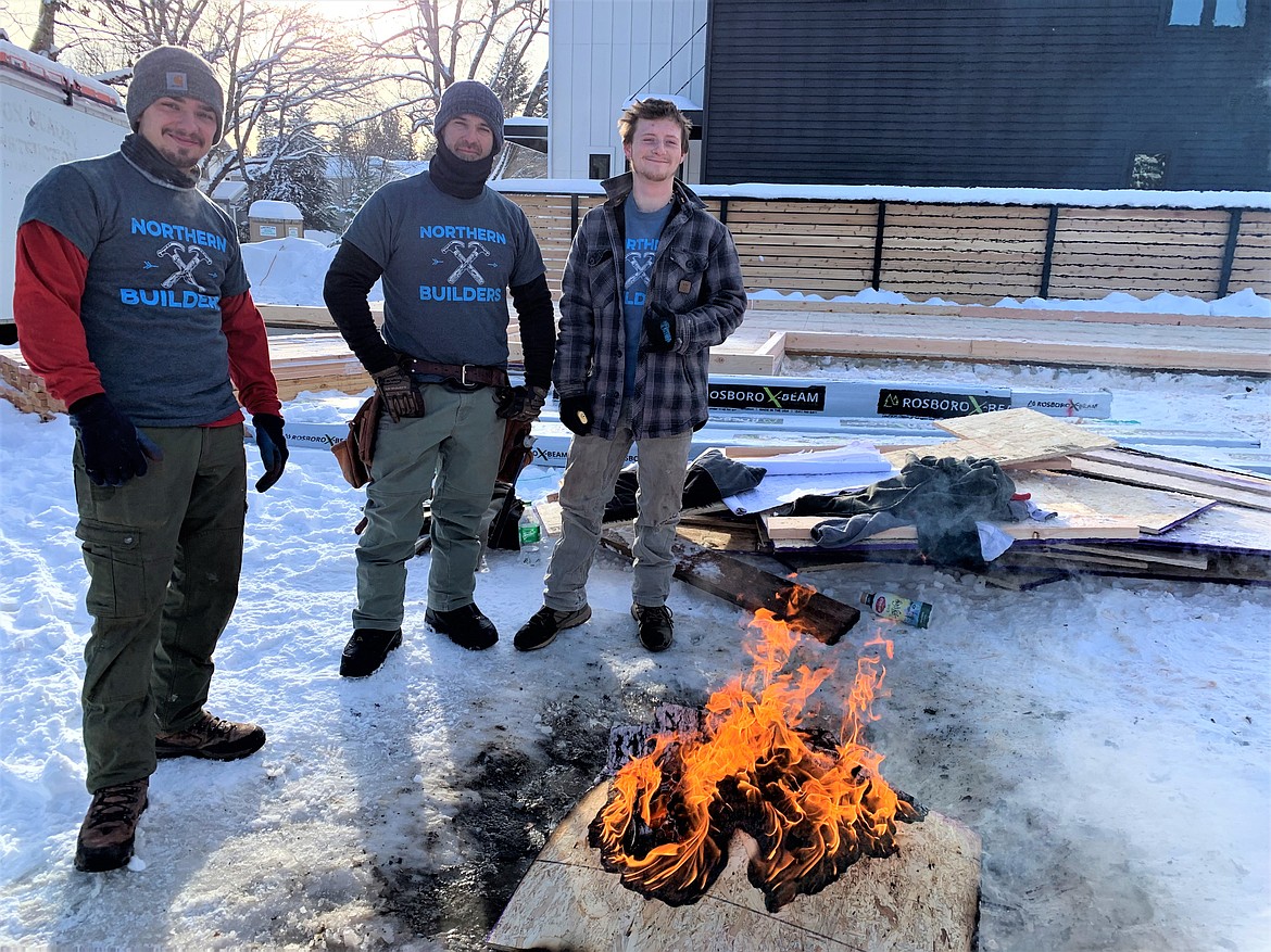 Northern Builders Jeffrey Fulton, left, David Merti and Gabriel Egge warm up Thursday morning around a fire at 17th and Mullan, where they are building a home.