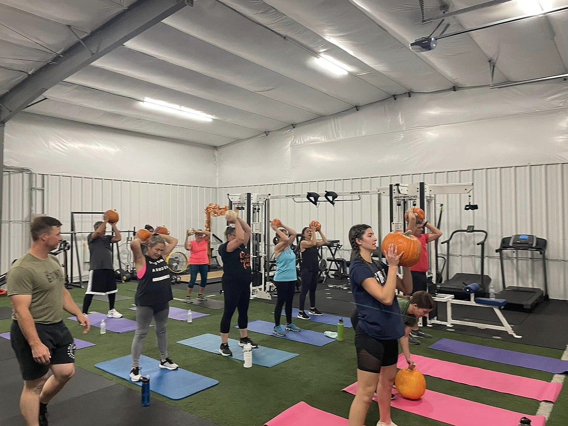 Gymgoers use pumpkins as part of a workout during a themed class in October 2022.