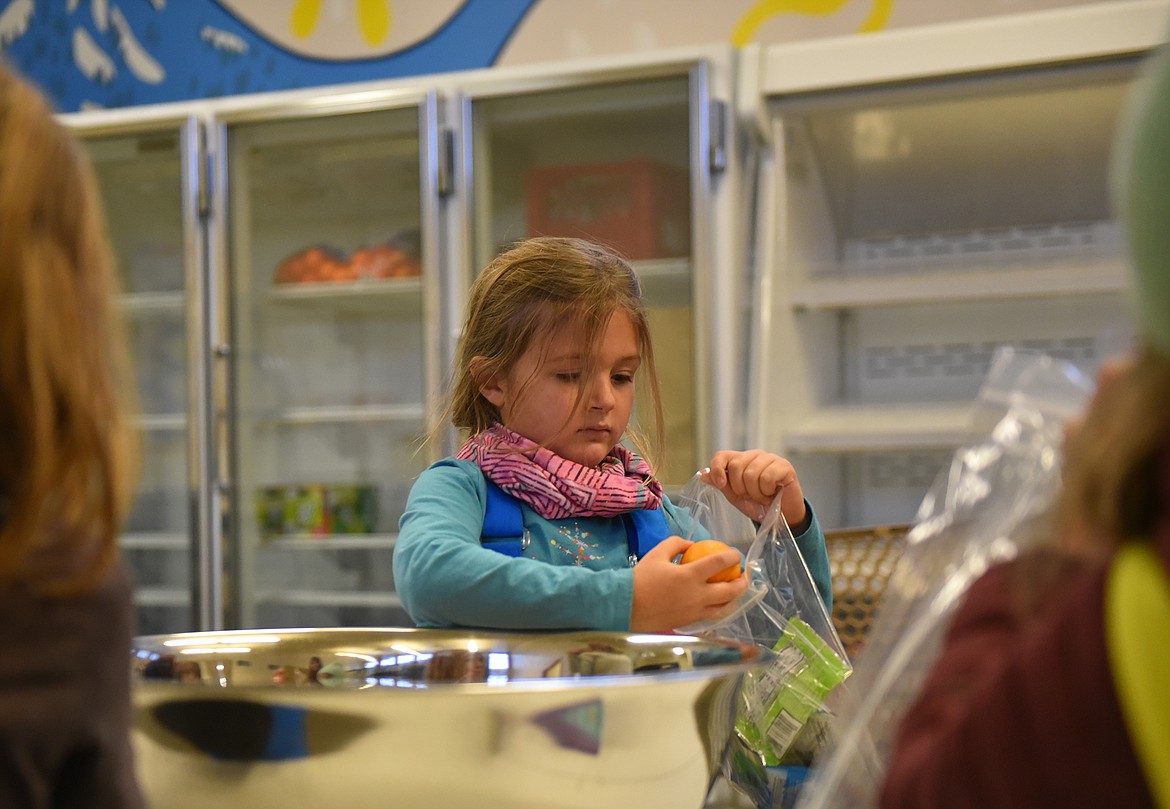 First grader Aspen Paine helps assemble snack bags at North Valley Food Bank. (Julie Engler/Whitefish Pilot)