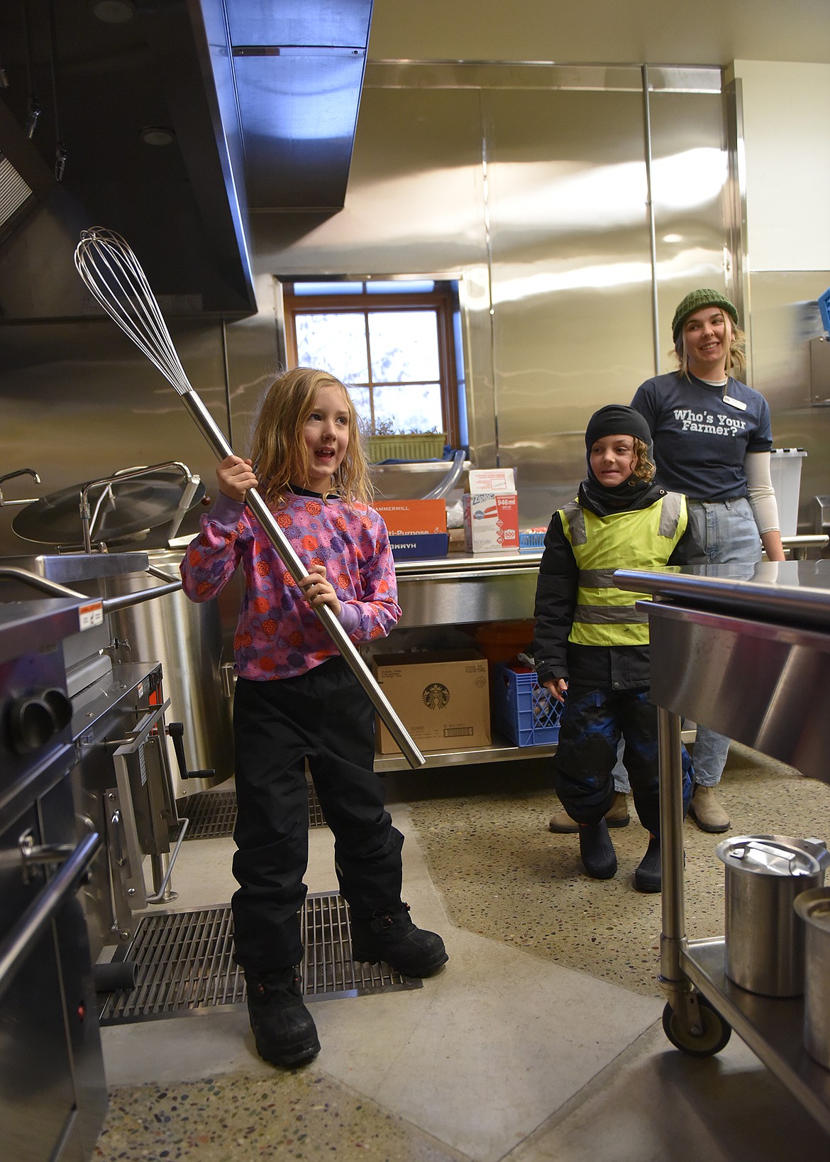 Gus Johnson holds a large whisk at the food bank while student Bodhi Regan and AmeriCorps Vista, Maddie Culhane stand by. (Julie Engler/Whitefish Pilot)