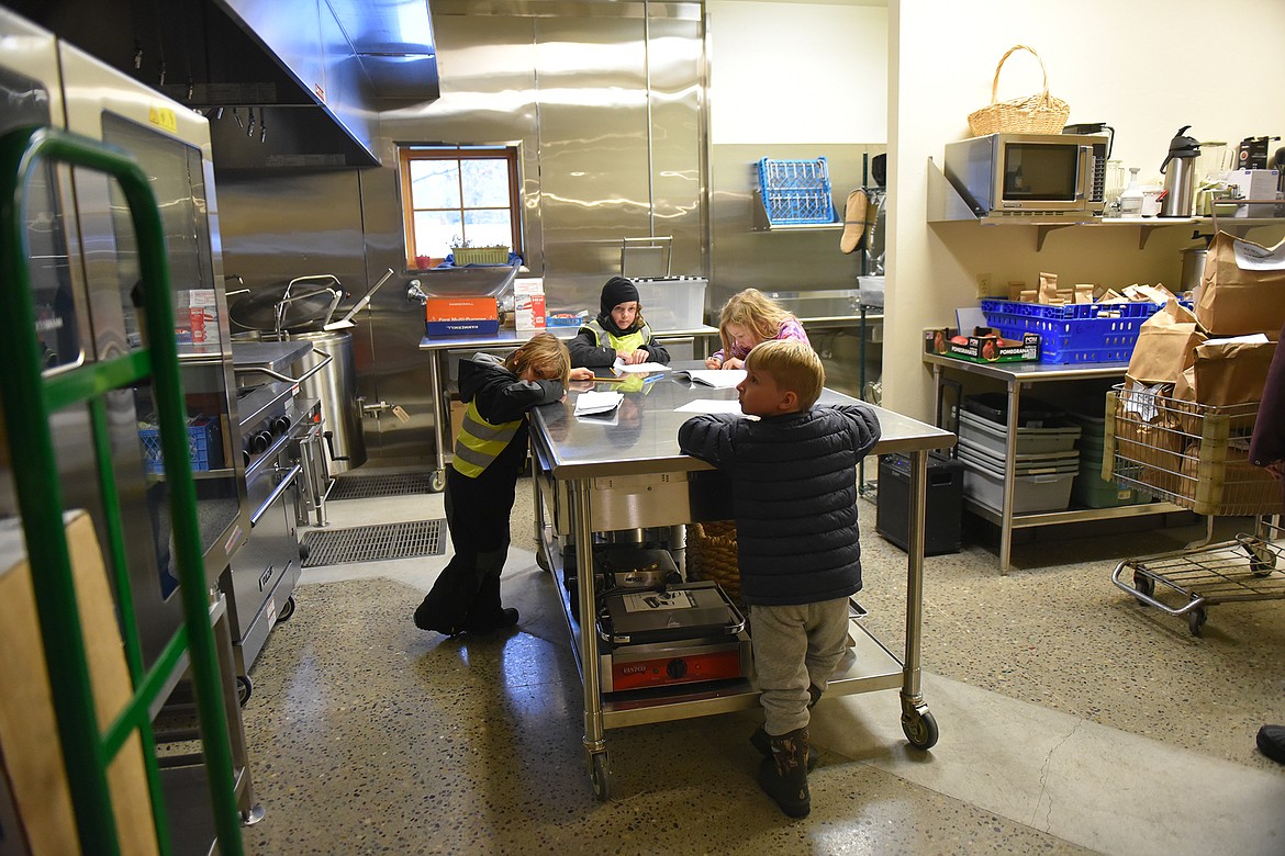 Students, from left, clockwise, Luca Spagna, Bodhi Regan, Gus Johnson and Beau Ober work on drawings in the North Valley Food Bank recently. (Julie Engler/Whitefish Pilot)