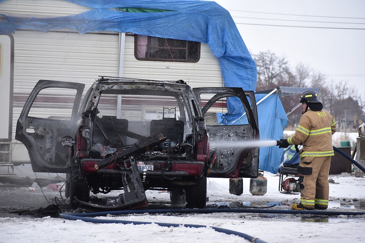 A Moses Lake Fire Department firefighter sprays water on a burned vehicle Monday afternoon in the 4300 block of Miller Street Northeast.