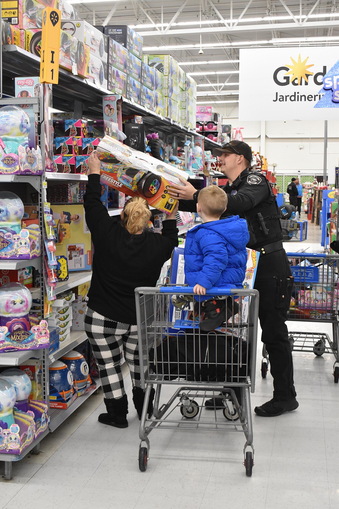 SLPD officer Trevor Jones helps a parent pull a large toy off a shelf.