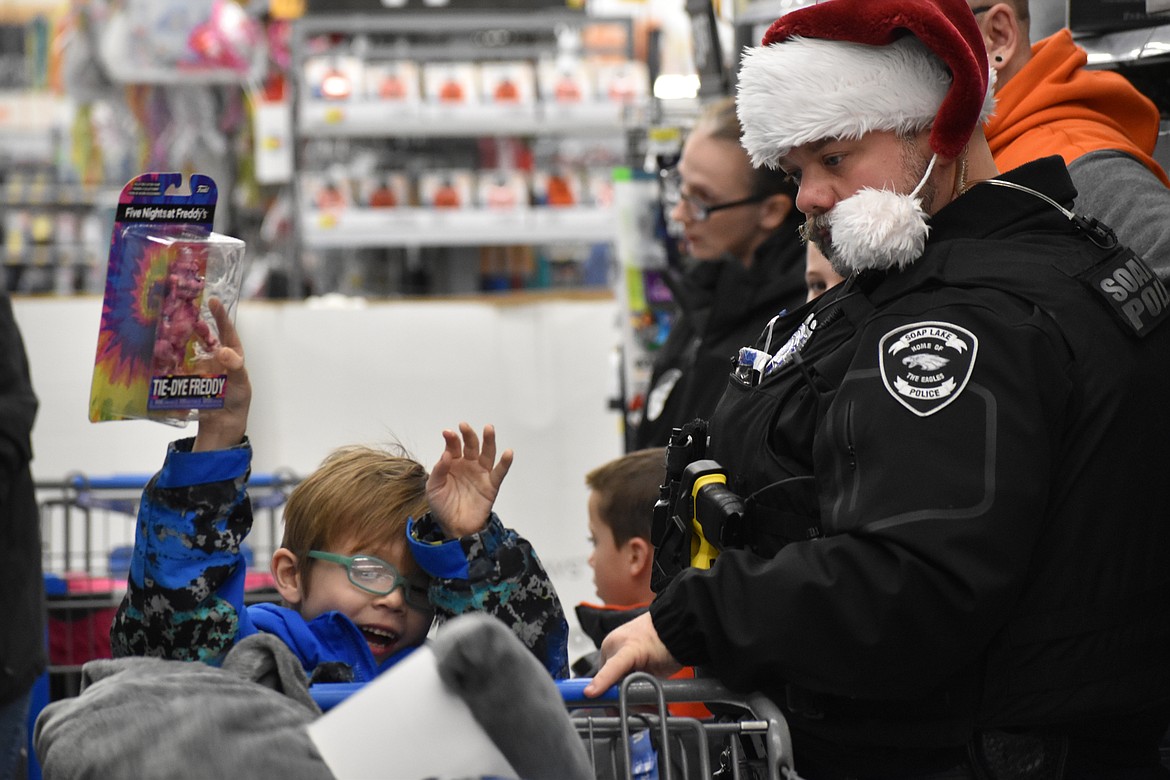 SLPD Officer Justin Rowland watches as a child excitedly puts a toy in the cart.