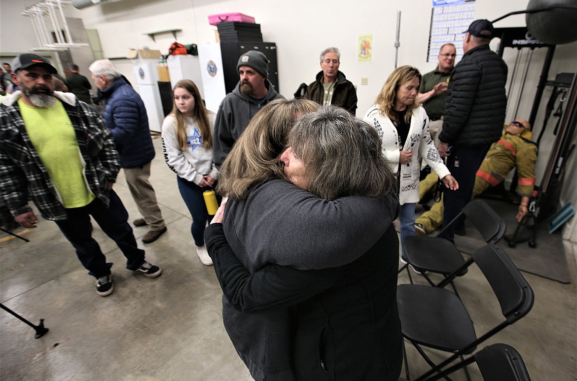 Karen Kubani of Hauser hugs Joanne Rogers following a town hall meeting at the Hauser Lake Fire Station, while John Stephen Hazell, Jr., left, looks on.