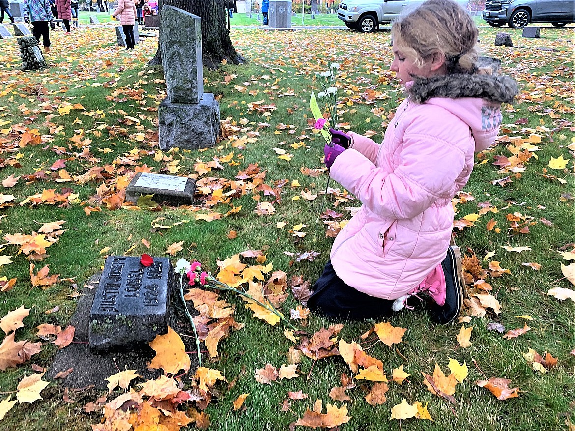 Annie Aberle, a third-grader at Holy Family Catholic School, prays on All Souls Day at St. Thomas Catholic Cemetery in November.