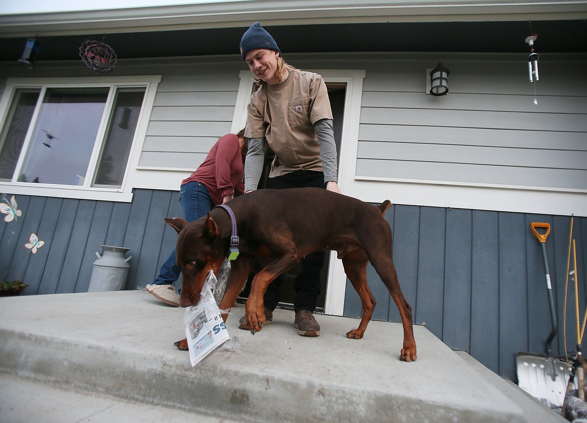 Doberman pinscher Bu brings the Coeur d'Alene Press to his boy, Trace Valente, on an early March 25 morning. The canine is a big fan of fetching the paper every day.