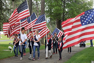 Members of American Heritage Girls and Trail Life boys with Real Life Ministries in Post Falls carry flags at Evergreen Cemetery.