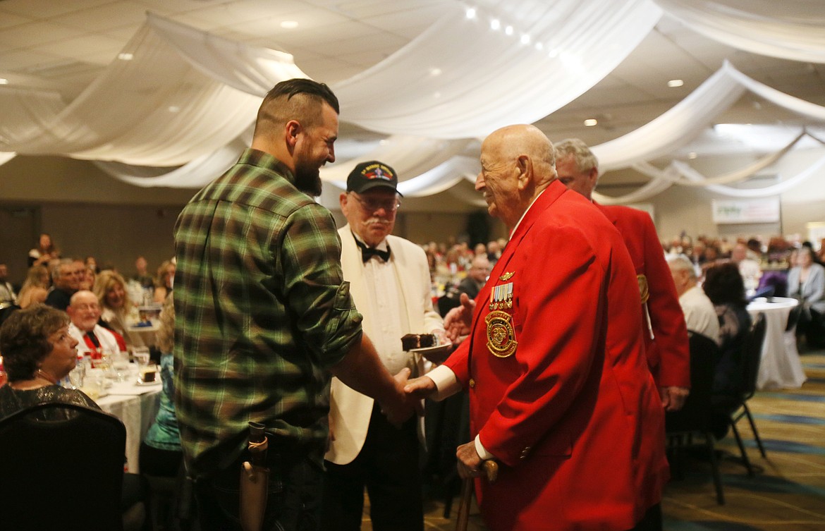 Ryan Clawson, 32, shakes hands with Noelan "Mac" McCormack, 86, as the youngest and oldest Marines in the room are acknowledged on Veterans Day during the Marine Corps Birthday Ball. Also pictured: Roy Kisner, 87, center.