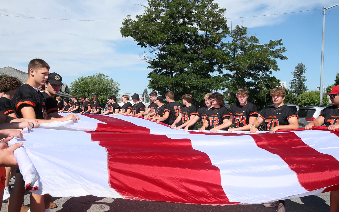 Post Falls High School football players gently unfurl a giant American flag before carrying it above their heads July 9 in the Post Falls Festival Parade.