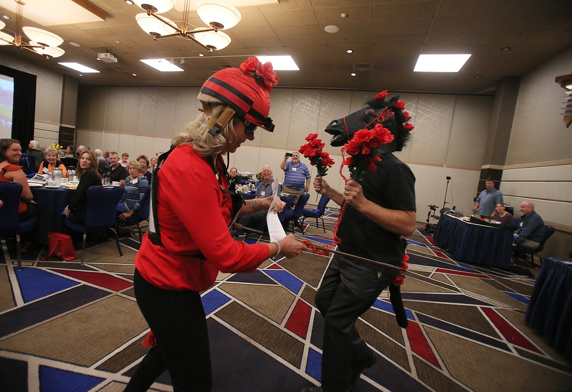 Coeur d'Alene Rotary Club President Candace Godwin, as Rosebud Thorn, gives her trusty horse Ponyboy, played by Rotarian Steve Roberge, a friendly paddle with a horse crop Sept. 16 as the two gallop into the room to announce the start of the Rotary Rose Sale.