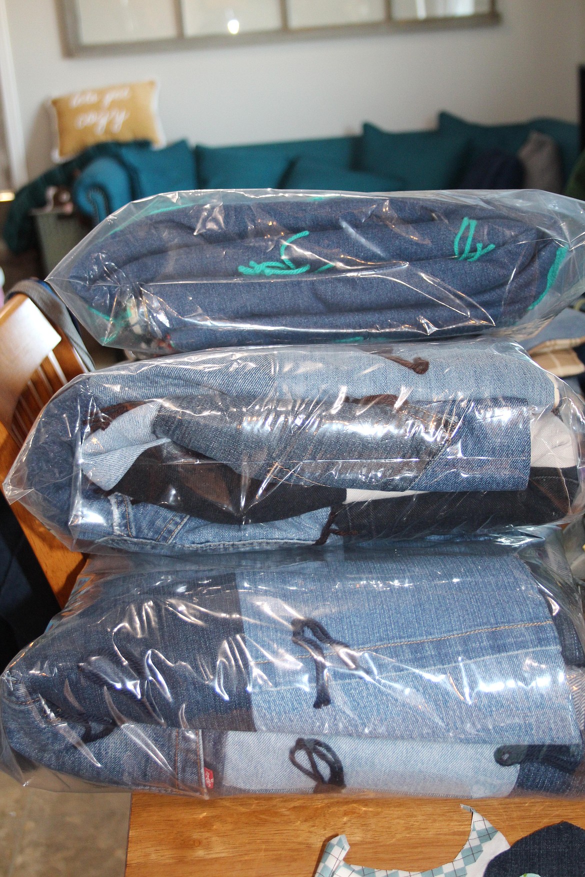 Ready for delivery, custom quilts sit on a table in Keri Perez’s sewing area.