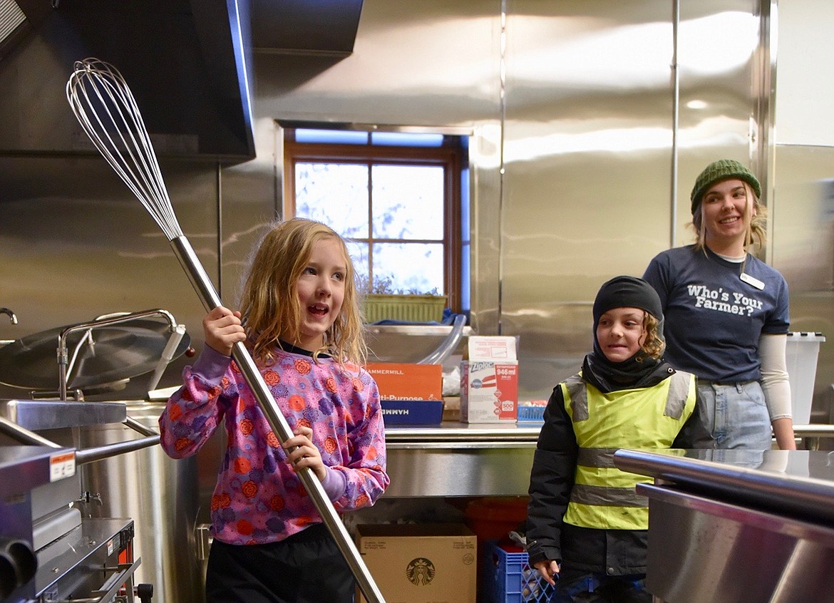 Gus Johnson holds a large whisk at the food bank while student Bodhi Regan and AmeriCorps Vista, Maddie Culhane stand by. (Julie Engler/Whitefish Pilot)