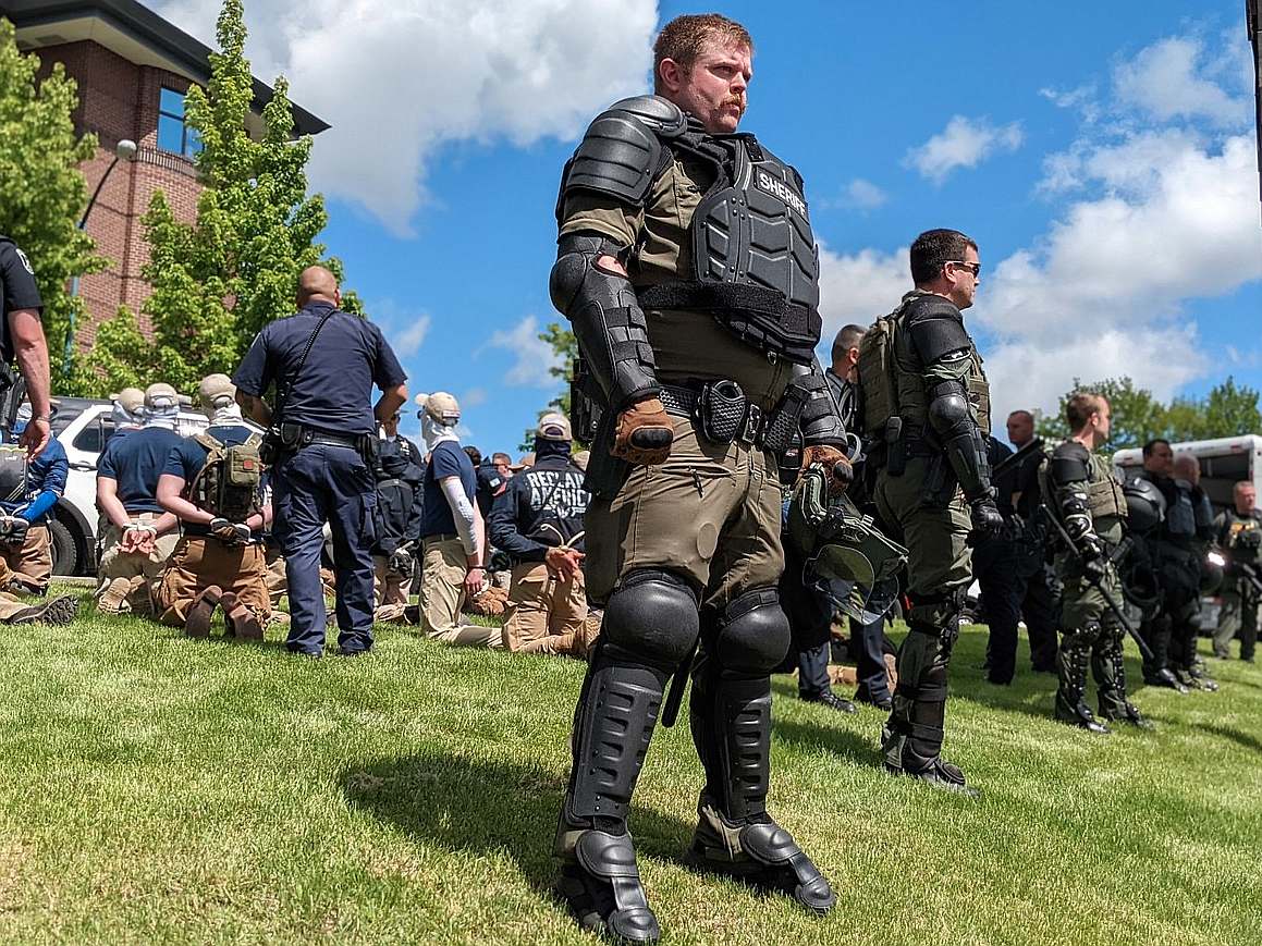 Kootenai County Sheriff's Office personnel in riot gear guard Coeur d'Alene Police officers who arrested the individuals seen kneeling with their hands cuffed behind their backs June 11 in Coeur d'Alene. Those arrested are associated with the Patriot Front, a white nationalist, fascist organization.