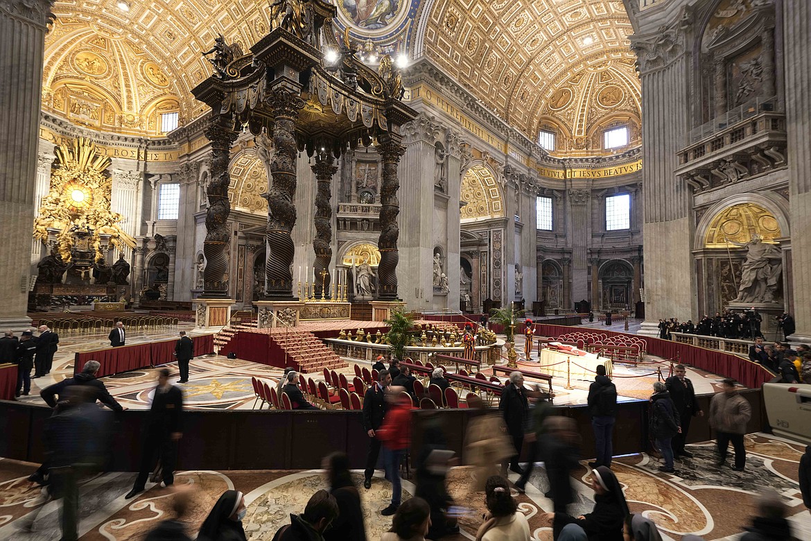 People look at the body of late Pope Emeritus Benedict XVI laid out in state inside St. Peter's Basilica at The Vatican, Monday, Jan. 2, 2023. Benedict XVI, the German theologian who will be remembered as the first pope in 600 years to resign, has died, the Vatican announced Saturday. He was 95. (AP Photo/Andrew Medichini)