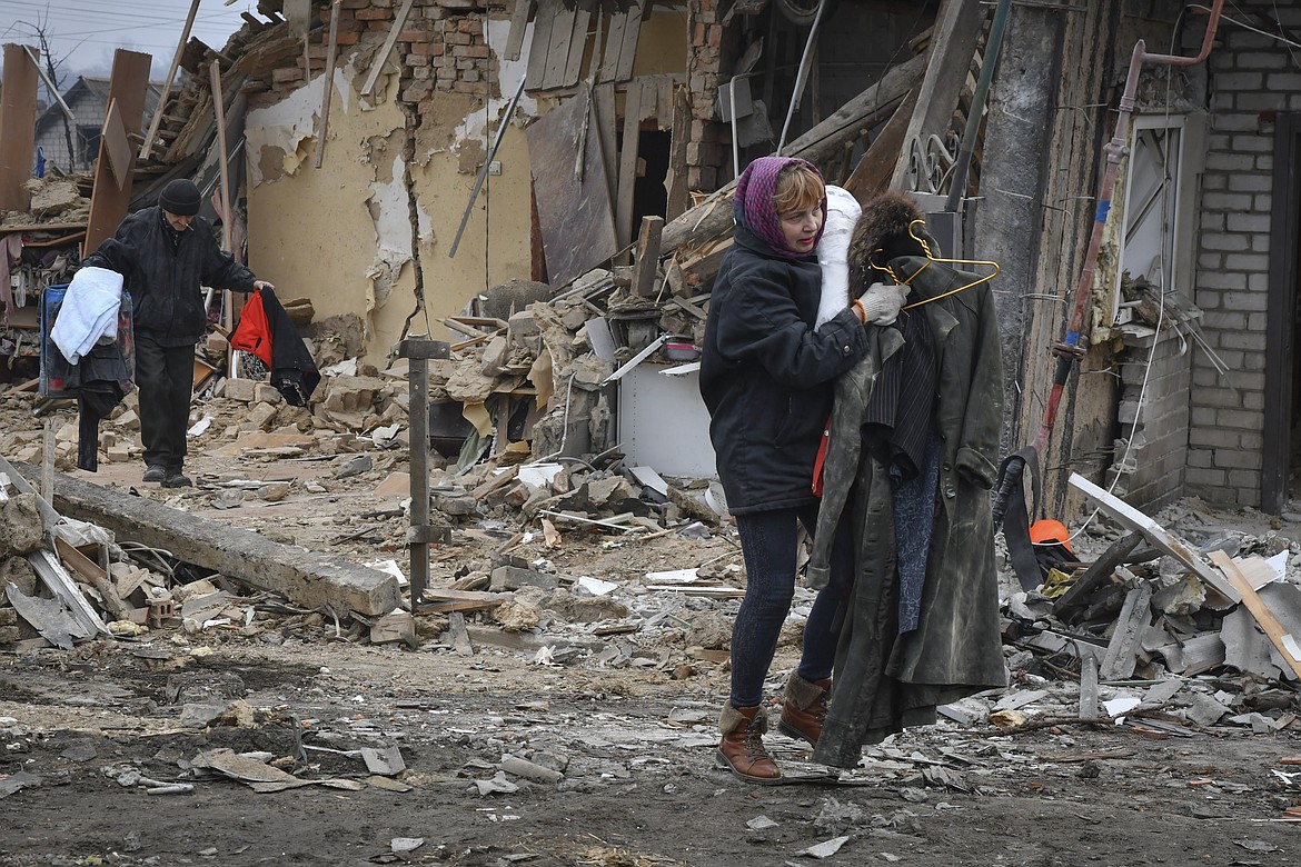 Local residents carry their belongings as they leave their home ruined in the Saturday Russian rocket attack in Zaporizhzhya, Ukraine, Sunday, Jan. 1, 2023. (AP Photo/Andriy Andriyenko)